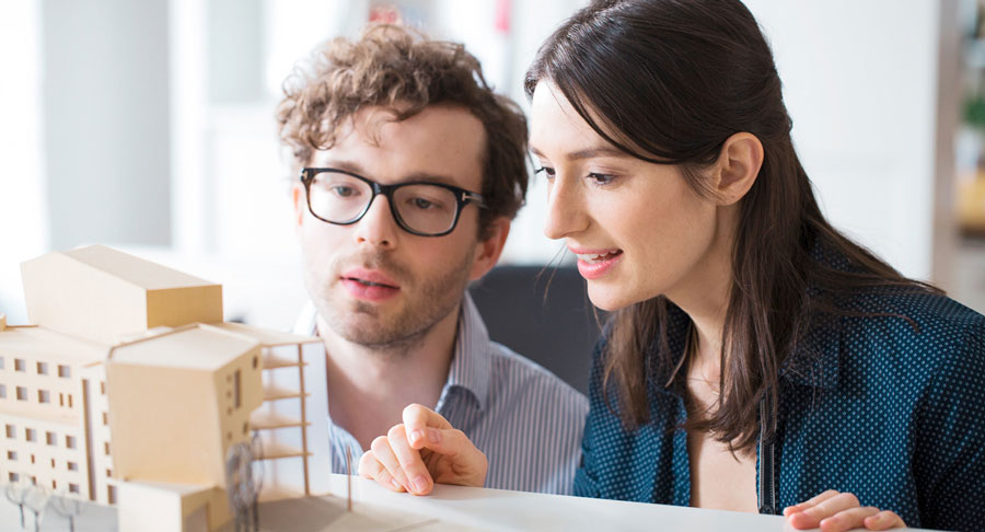 Das Bild zeigt einen Mann und eine Frau die ein Modell eines Gebäudes betrachten