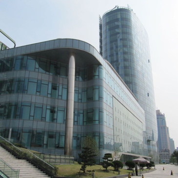 Auf dem Bild ist der Shanghai Port zu sehen ein geschwungenes Gebäude mit Glasfassade und einem höheren Turmgebäude