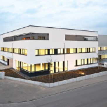 auf dem Bild is das Gebäude der Simpson Strong-Tie GmbH in Bad-Nauheim zu sehen ein weißes Gebäude mit flachdach und vielen Fenstern