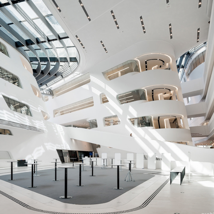 Auf dem Bild ist das Innere der Wirtschaftsuniversität Wien zu sehen ein schiefes in weiß gehaltenes Gebäude mit vielen Rundungen im Inneren