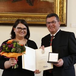 Das Bild zeigt wie Ramona Meinzer Geschäftsführerin von Aumüller mit der bayerischen Staatsmedaille für besondere Verdienste um die bayerische Wirtschaft vom bayrischen Wirtschaftsminister ausgezeichnet wird
